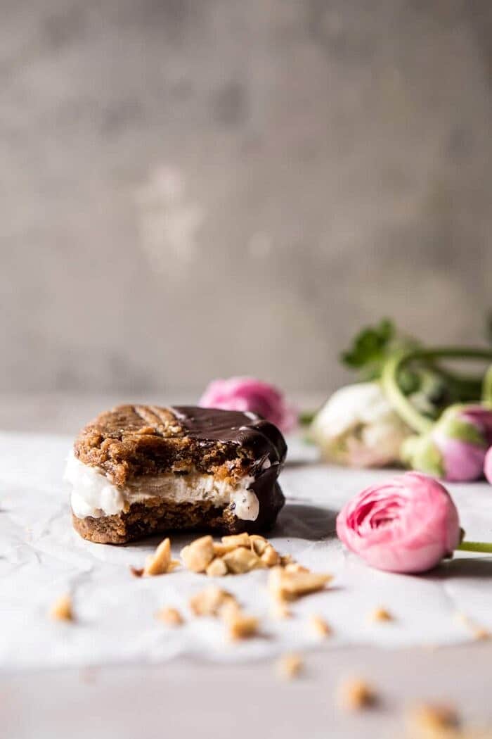 Chocolate Dipped Peanut Cookie Ice Cream Sandwiches | halfbakedharvest.com #icecream #chocolate #peanutbutter #summer front on photo of Chocolate Dipped Peanut Cookie Ice Cream Sandwiches with bite in sandwich
