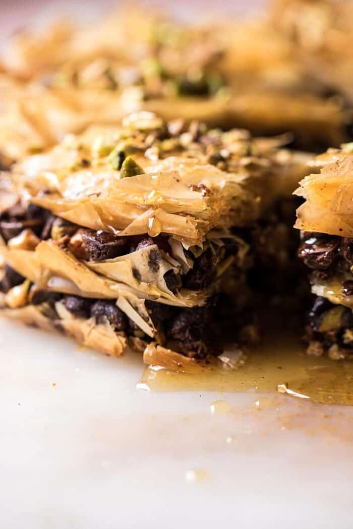 side angle photo of Easy Pistachio Chocolate Baklava with honey dripping down