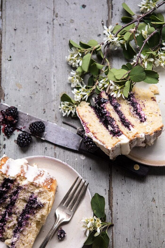 Blackberry Lavender Naked Cake with White Chocolate Buttercream | halfbakedharvest.com #summerrecipes #layercake #blueberries overhead photo of Blackberry Lavender Naked Cake with two cake pieces in photo