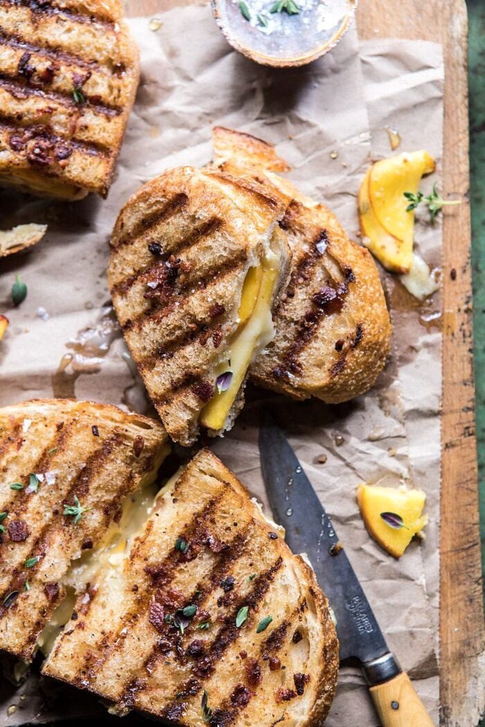 Honey, Peach, and Brie Panini with Bacon Butter | halfbakedhavrest.com #grilledcheese #peaches #easyrecipes #summer side angle photo of Honey, Peach, and Brie Panini with Bacon Butter cut in half to show the brie and peaches