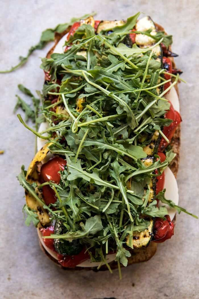 Marinated Veggie Cheese Sandwich with Sun-Dried Tomato Pesto | halfbakedharvest.com #easyrecipe #summer #sandwhich #healthyrecipes #dinner #easy #lunch overhead photo of Marinated Veggie Cheese Sandwich with Sun-Dried Tomato Pesto and arugula on top