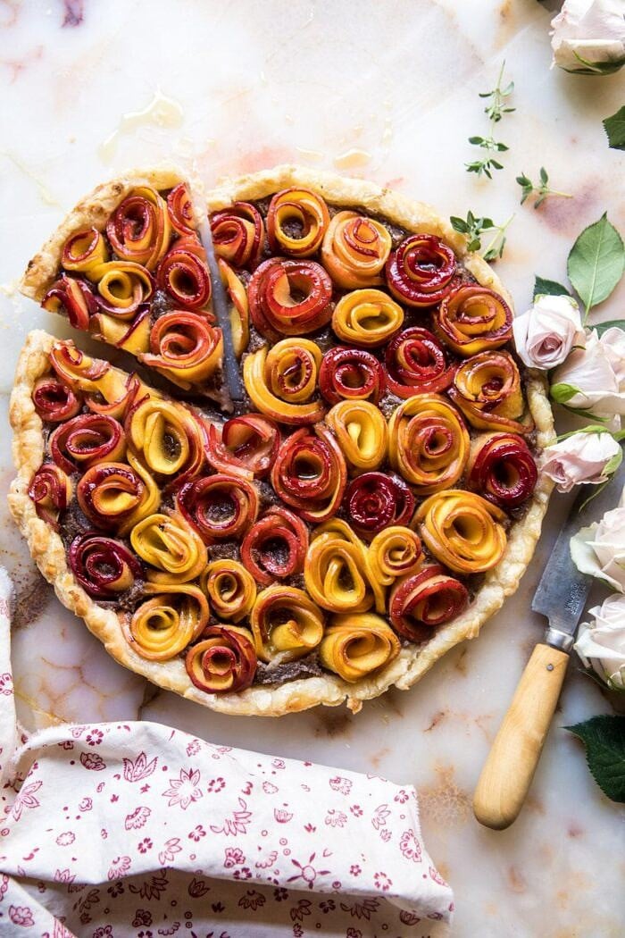 Sweet Peach Rose Tart | halfbakedharvest.com #peach #summerrecipes #tart #summer #pie overhead photo of Sweet Peach Rose Tart with 1 piece cut, knife, and roses in photo