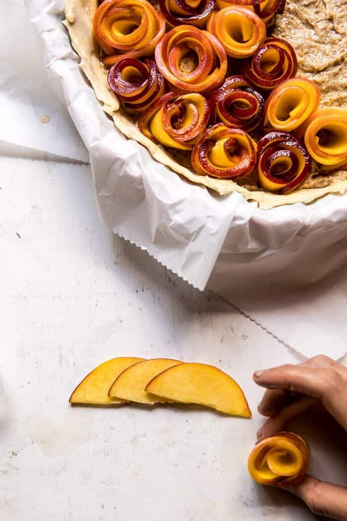 Sweet Peach Rose Tart | halfbakedharvest.com #peach #summerrecipes #tart #summer #pie rolling peach slices into roses, overhead prep photo