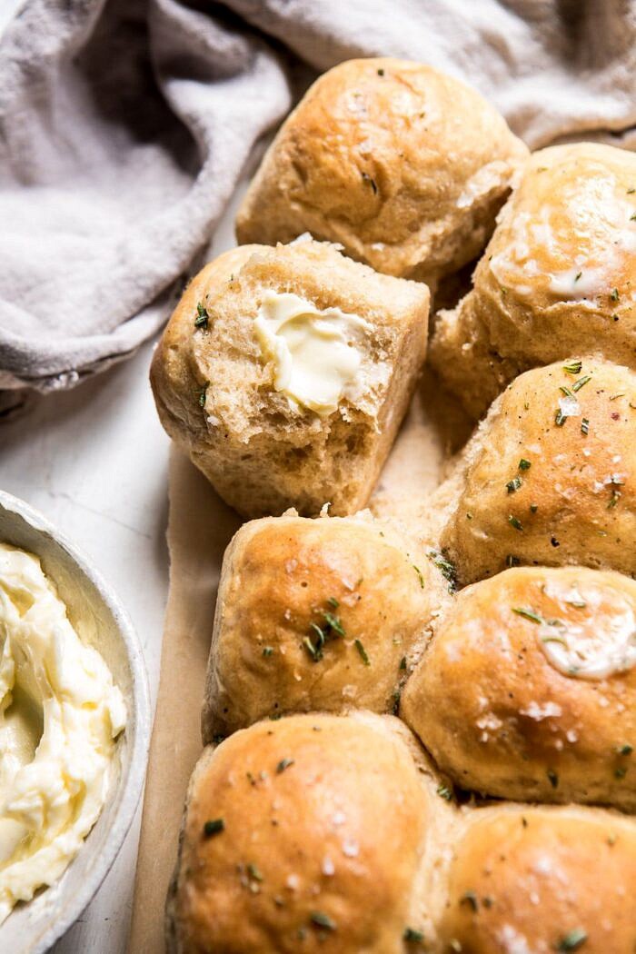 Buttery Pull Apart Whole Wheat Potato Rolls | halfbakedharvest.com #bread #rolls #easyrecipes #backtoschool side angle photo of Buttery Pull Apart Whole Wheat Potato Rolls with butter on roll