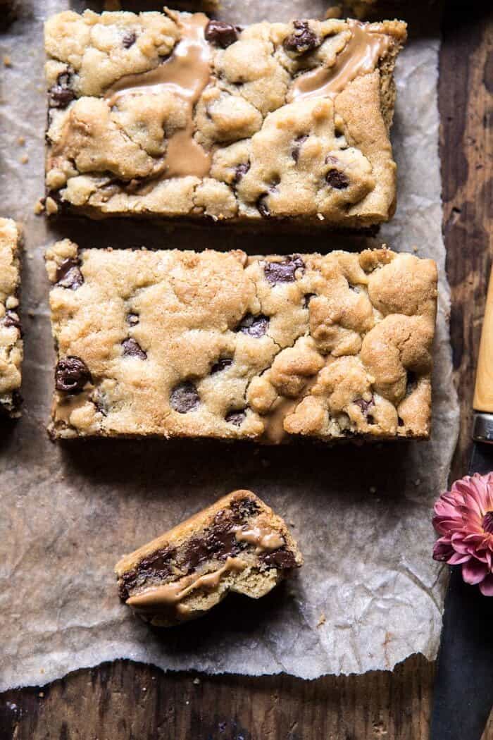 The Best Chocolate Chip Peanut Butter Swirled Cookie Bars | halfbakedharvest.com #cookies #cookiebars #peanutbutter #chocolate close up photo of Chocolate Chip Peanut Butter Swirled Cookie Bars with flower and knife in photo