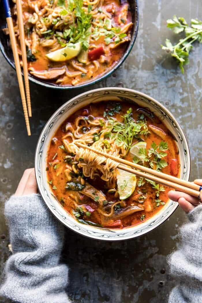 30 Minute Thai Peanut Chicken Ramen | halfbakedharvest.com #soup #instantpot #ramen #fallrecipes overhead photo 30 Minute Thai Peanut Chicken Ramen with hand on bowl pulling noodles out of bowl