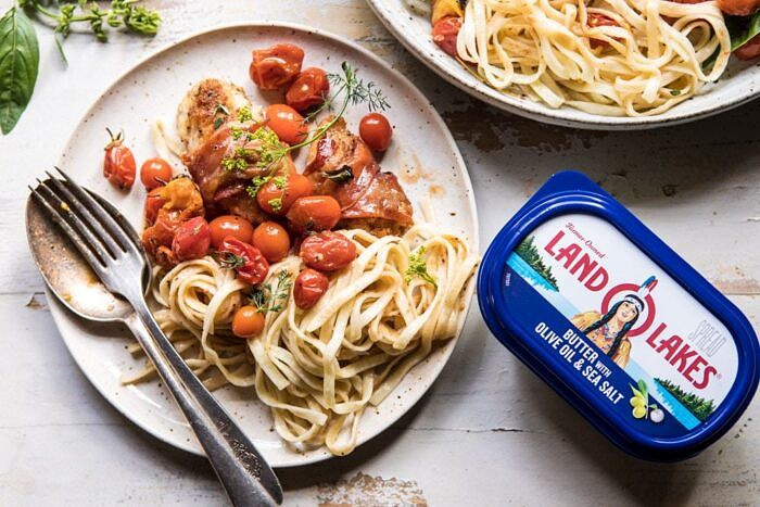 horizontal photo of Prosciutto Chicken Parmesan with Garlic Butter Tomato Pasta on plate with butter in photo 