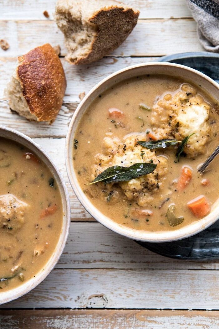 overhead close up photo of One Pot Chicken and Sage Dumplings with bread on table and spoon in bowl