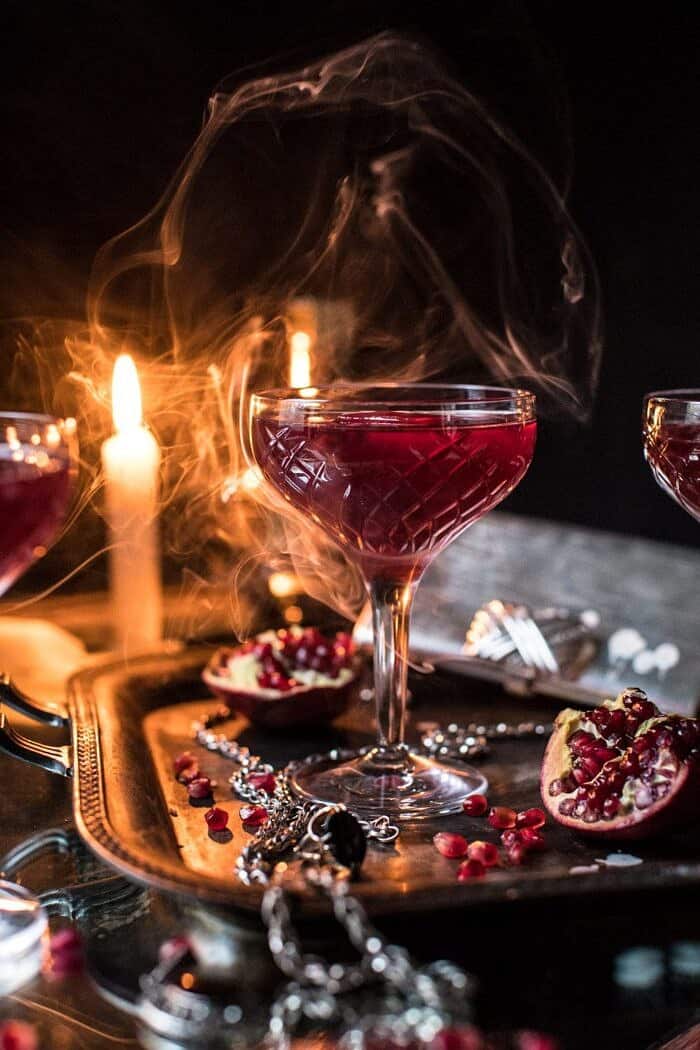 The Half Blood Prince Cocktail | halfbakedharvest.com #cocktails #halloween #pomegranate #fall #autumn front on shot of The Half Blood Prince Cocktail with smoke and candles in photo