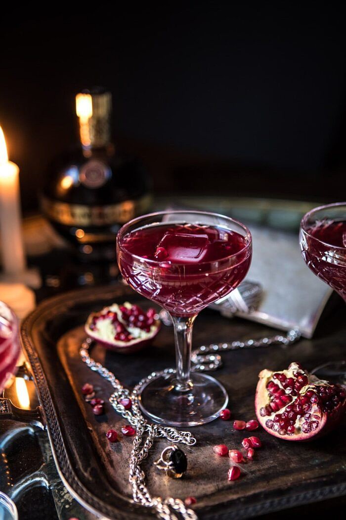 The Half Blood Prince Cocktail | halfbakedharvest.com #cocktails #halloween #pomegranate #fall #autumn 3/4 angle photo of The Half Blood Prince Cocktail with candles in photo