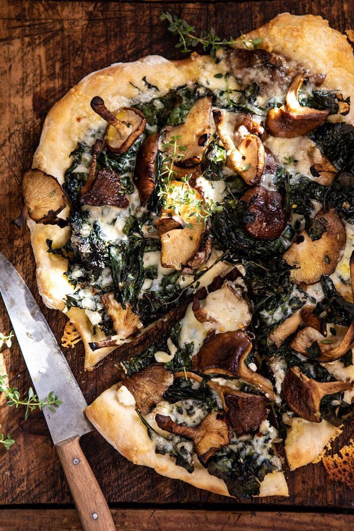 Roasted Mushroom Kale Pizza | halfbakedharvest.com #pizza #mushrooms #winter #fall #autumn #kale #Italian overhead close up photo of Roasted Mushroom Kale Pizza with slice cut and knife in photo