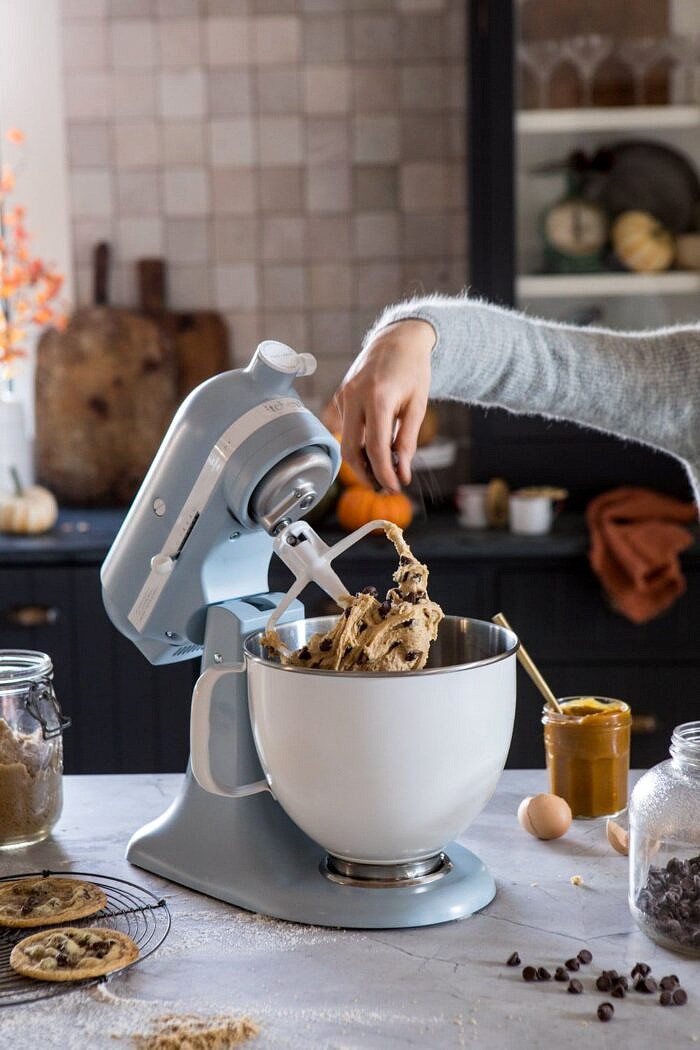 Celebrating 100 Years of KitchenAid | halfbakedharvest.com #giveaway #cookies KitchenAid stand mixer in counter with cookie dough in bowl and chocolate chips being added to the bowl