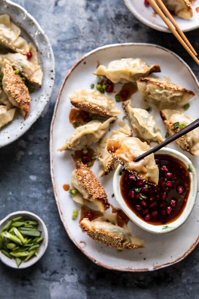 Ginger Sesame Chicken Potstickers with Sweet Chili Pomegranate Sauce | halfbakedharvest.com #asianrecipes #potstickers #dumplings #healthy overhead photo of Ginger Sesame Chicken Potsticker being held by chopstick