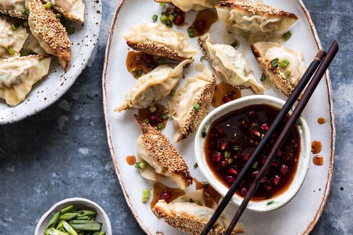 Ginger Sesame Chicken Potstickers with Sweet Chili Pomegranate Sauce | halfbakedharvest.com #asianrecipes #potstickers #dumplings #healthy horizontal photo of Ginger Sesame Chicken Potstickers with Sweet Chili Pomegranate Sauce on plate with chopsticks