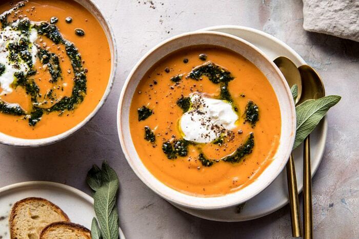 Golden Sweet Potato Soup with Burrata and Sage Pesto | halfbakedharvest.com #sweetpotato #soup #healthy #fall #autumn #winter #thanksgiving horizontal photo of Golden Sweet Potato Soup with Burrata and Sage Pesto with bread on table