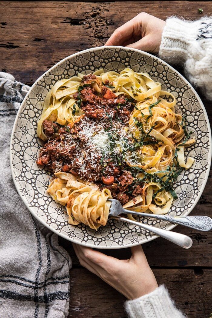 Slow Cooker Vodka Bolognese Pasta | halfbakedharvest.com #pasta #italian #bolognese #slowcooker overhead photo of Slow Cooker Vodka Bolognese Pasta with hands on bowl