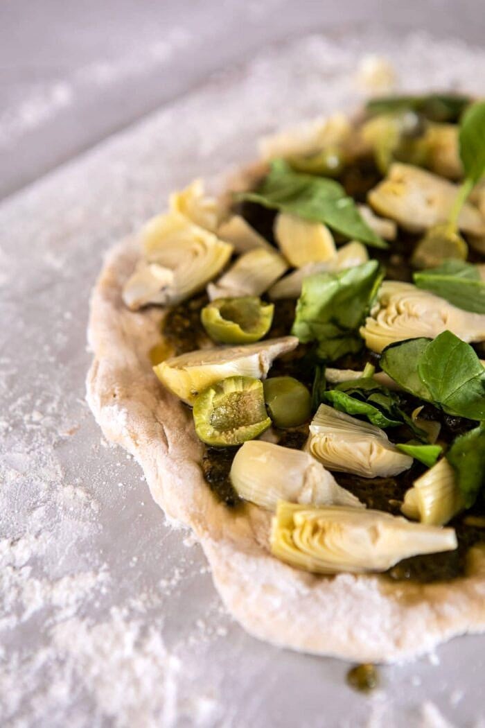 Artichoke Pesto and Burrata Pizza with Lemony Arugula | halfbakedharvest.com #pizza #healthy #burrata #easyrecipes side angled photo Artichoke Pesto and Burrata Pizza before baking