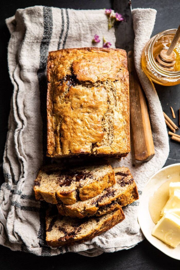 Chocolate Chunk Coconut Banana Bread | halfbakedharvest.com #bananabread #easyrecipes #healthyrecipes #chocolate #dessert over head photo of sliced Chocolate Chunk Coconut Banana Bread with honey jar and butter on table
