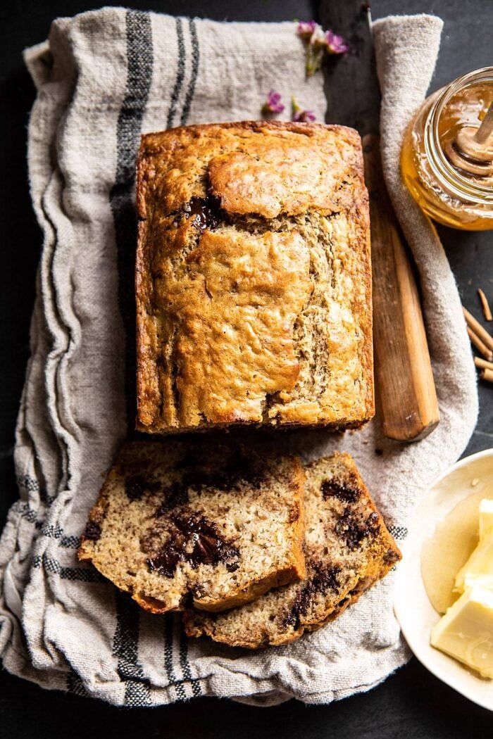Chocolate Chunk Coconut Banana Bread | halfbakedharvest.com #bananabread #easyrecipes #healthyrecipes #chocolate #dessert Chocolate Chunk Coconut Banana Bread with 2 pieces cut and honey in photo