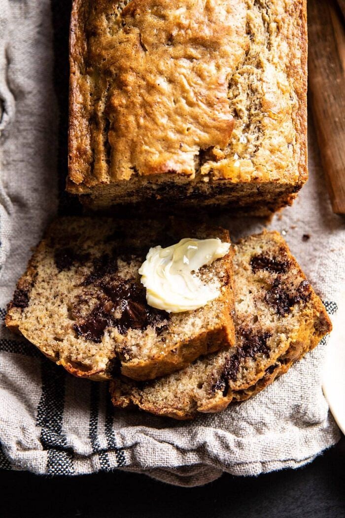 Chocolate Chunk Coconut Banana Bread | halfbakedharvest.com #bananabread #easyrecipes #healthyrecipes #chocolate #dessert overhead close up of Chocolate Chunk Coconut Banana Bread sliced with butter