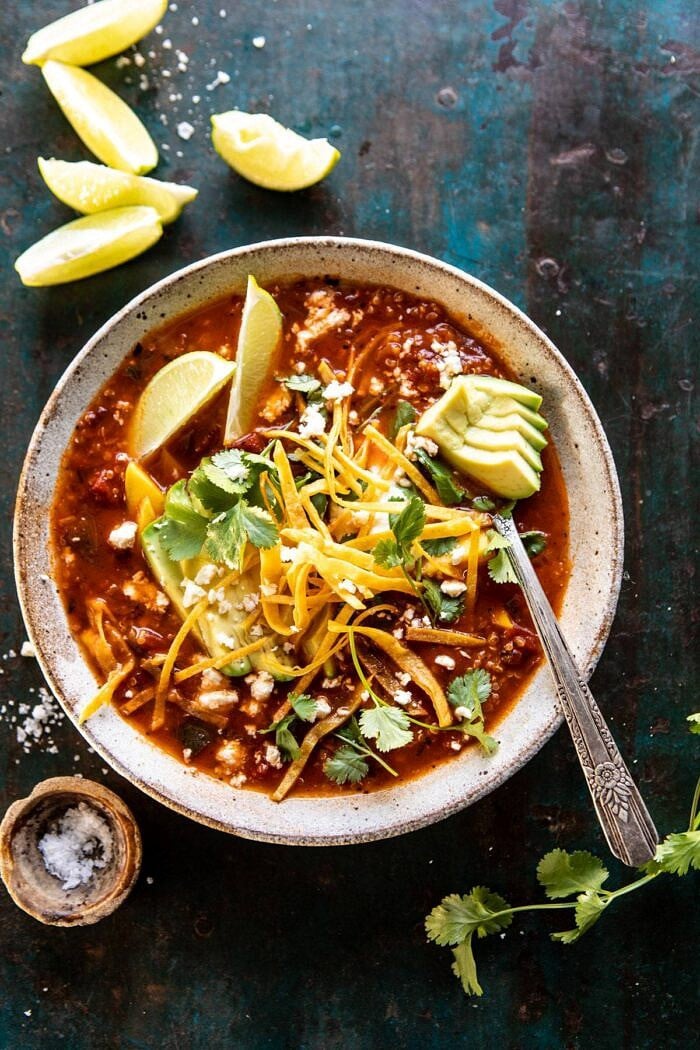 Crockpot Spicy Vegetarian Tortilla Soup with Quinoa | halfbakedharvest.com #crockpot #slowcooker #easyrecipes #healthyrecipes #healthyjanuary #mexican #soup overhead photo of Crockpot Spicy Vegetarian Tortilla Soup with Quinoa with spoon in bowl and limes on table