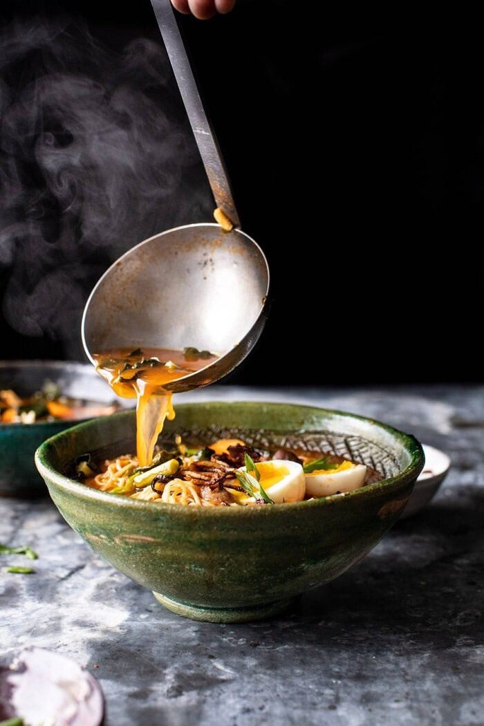 Feel Good Spicy Ramen with Sweet Potatoes and Crispy Shallots | halfbakedharvest.com #noodles #ramen #healthyrecipes #sweetpotatoes #winterrecipes #soup side angle photo of Feel Good Spicy Ramen begin poured into bowls