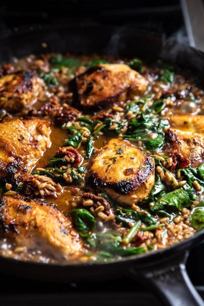 One Skillet Greek Sun-Dried Tomato Chicken and Farro | halfbakedharvest.com #skilletrecipes #chicken #healthyrecipes #onepan #easyrecipes side angle photo One Skillet Greek Sun-Dried Tomato Chicken and Farro on stovetop