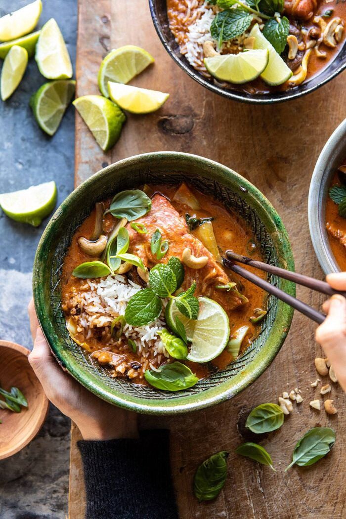Saucy 30 Minute Thai Basil Salmon Curry | halfbakedharvest.com #healthyrecipes #salmon #curry #winterrecipes #thairecipes overhead photo of Saucy 30 Minute Thai Basil Salmon Curry with hands on bowl