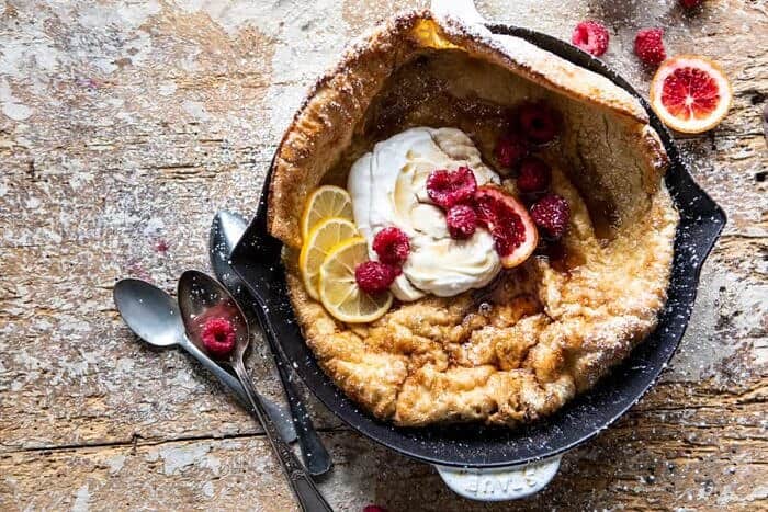 overhead photo of Whole Wheat Dutch Baby with Meyer Lemon Whipped Ricotta with berries and spoon on surface