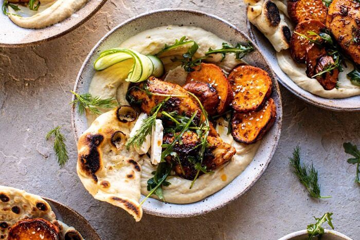 horizontal photo of Sheet Pan Chicken Shawarma with Sesame Sweet Potatoes and Hummus in bowls