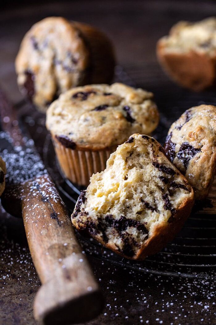 Cheesecake Stuffed Chocolate Chunk Banana Bread Muffins | halfbakedharvest.com #muffins #cheesecake #bananamuffin #dessert side angle photo of Cheesecake Stuffed Chocolate Chunk Banana Bread Muffin cut in half