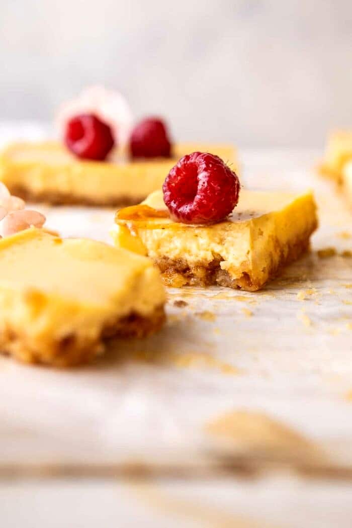 Creamy Lemon Bars with Browned Butter Raspberries | halfbakedharvest.com #lemon #brownbutter #spring #summer #easter #mothersday #brunch #dessert side angled photo of broken in half Creamy Lemon Bars with Browned Butter Raspberries