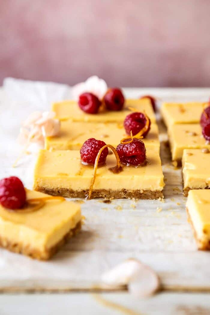Creamy Lemon Bars with Browned Butter Raspberries | halfbakedharvest.com #lemon #brownbutter #spring #summer #easter #mothersday #brunch #dessert side angle photo of Creamy Lemon Bars with Browned Butter Raspberries