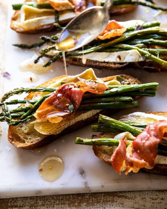 Crispy Prosciutto, Asparagus, and Brie Toast | halfbakedharvest.com #easyrecipes #appetizers #brie #mothersday #spring #summer side angled photo of Crispy Prosciutto, Asparagus, and Brie Toast with honey being drizzled over the toast