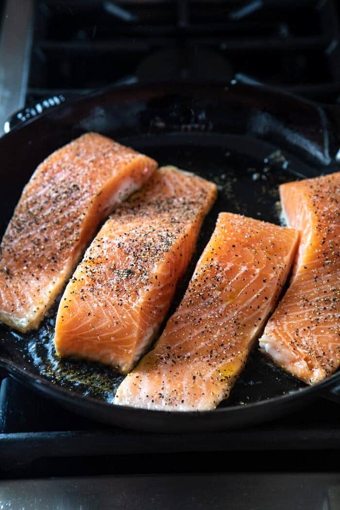Garlic Butter Creamed Spinach Salmon | halfbakedharvest.com #salmon #easyrecipes #seafood #dinner raw salmon cooking in skillet
