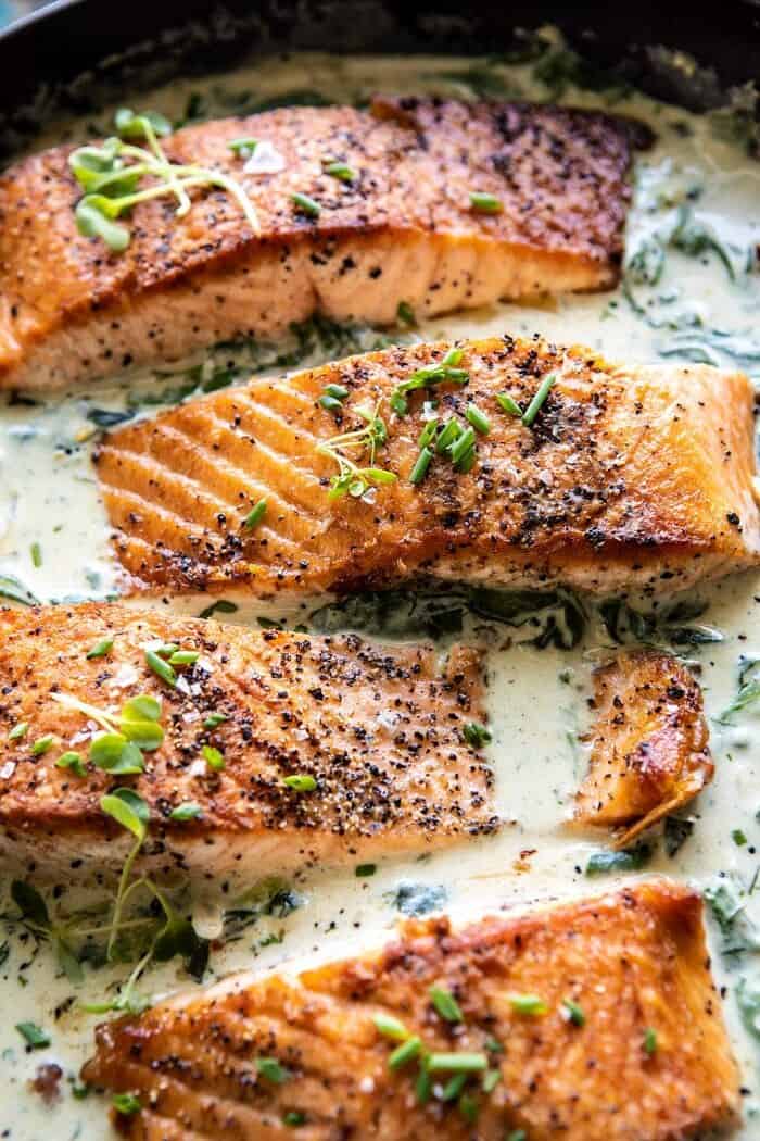 Garlic Butter Creamed Spinach Salmon | halfbakedharvest.com #salmon #easyrecipes #seafood #dinner side angled close up photo of Garlic Butter Creamed Spinach Salmon in skillet