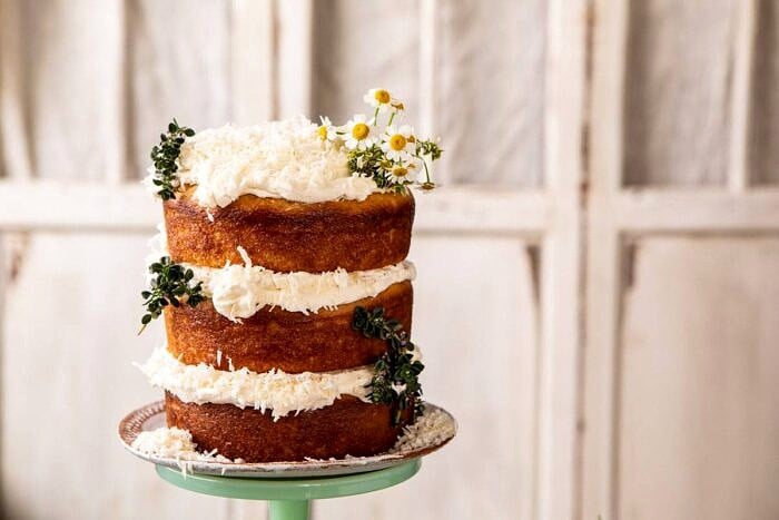Lemon Coconut Naked Cake with Whipped Vanilla Buttercream | halfbakedharvest.com #coconutcake #springrecipes #easter #cake #layercake horizontal photo of Lemon Coconut Naked Cake with Whipped Vanilla Buttercream