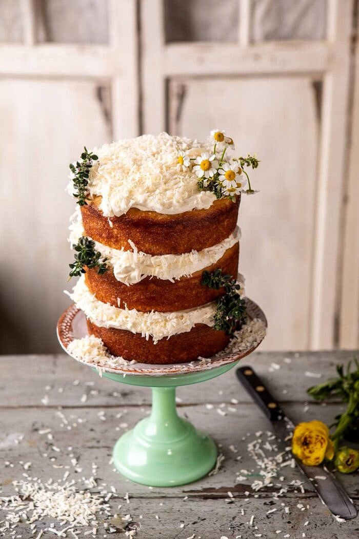 Lemon Coconut Naked Cake with Whipped Vanilla Buttercream | halfbakedharvest.com #coconutcake #springrecipes #easter #cake #layercake overhead photo of Lemon Coconut Naked Cake with Whipped Vanilla Buttercream on cake stand