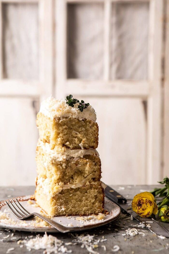 Lemon Coconut Naked Cake with Whipped Vanilla Buttercream | halfbakedharvest.com #coconutcake #springrecipes #easter #cake #layercake Lemon Coconut Naked Cake piece standing up on dessert plate with fork on plate