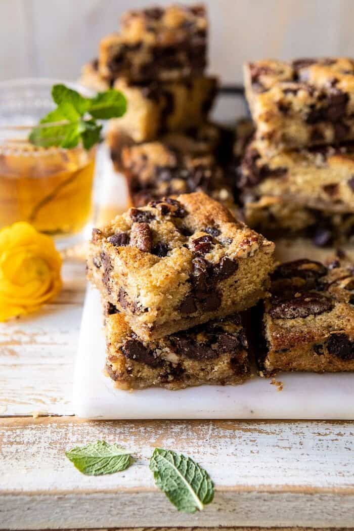 Kentucky Derby Pie Chocolate Chip Cookie Bars | halfbakedharvest.com #cookiebars #pecanpie #chocolatechip #dessert side angled of Kentucky Derby Pie Chocolate Chip Cookie Bars stacked on top of each other