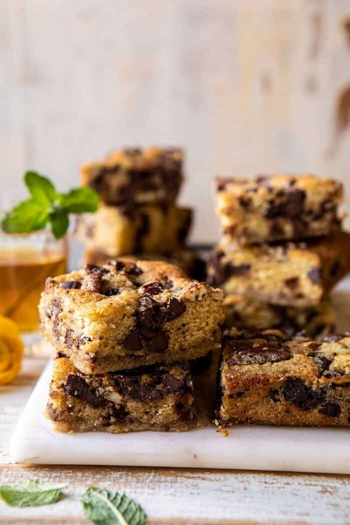 Kentucky Derby Pie Chocolate Chip Cookie Bars | halfbakedharvest.com #cookiebars #pecanpie #chocolatechip #dessert side angled photo of Kentucky Derby Pie Chocolate Chip Cookie Bars stacked on top of each other
