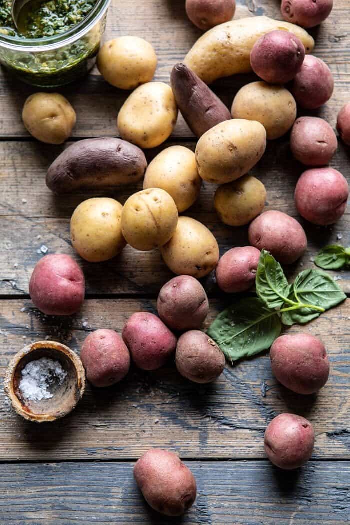 over head photo if raw potatoes with pesto jar in the corner 