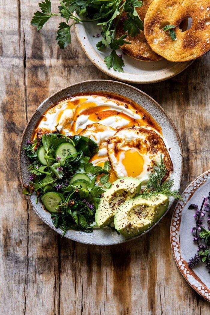 Turkish Eggs with Chile Butter and Whipped Feta | halfbakedharvest.com #breakfast #brunch #healthyrecipes #eggs #spring #summer overhead photo if Turkish Eggs with Chile Butter and Whipped Feta with bagel and greens in photo