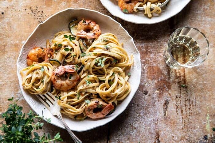 Garden Herb Shrimp Scampi Linguine | halfbakedharvest.com #pasta #shrimp #easyrecipes #summerrecipes horizontal photo of Garden Herb Shrimp Scampi Linguine with fork in bowl and wine glass on table