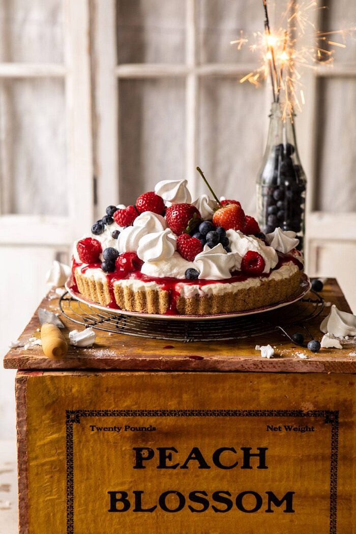 No-Bake Eton Mess Berry Cheesecake | halfbakedharvest.com #cheesecake #nonbake #easyrecipes #dessert #4thofjuly head on photo of No-Bake Eton Mess Berry Cheesecake with sparklers in background of photo