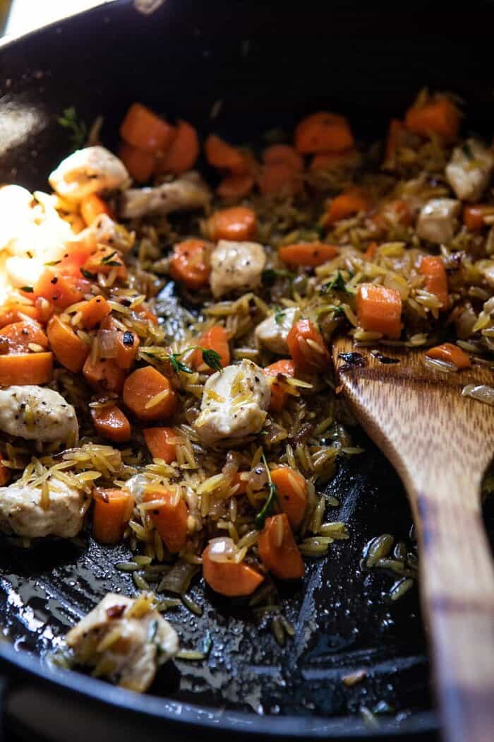 side angled photo of chicken and rice in skillet on the stove before adding liquid