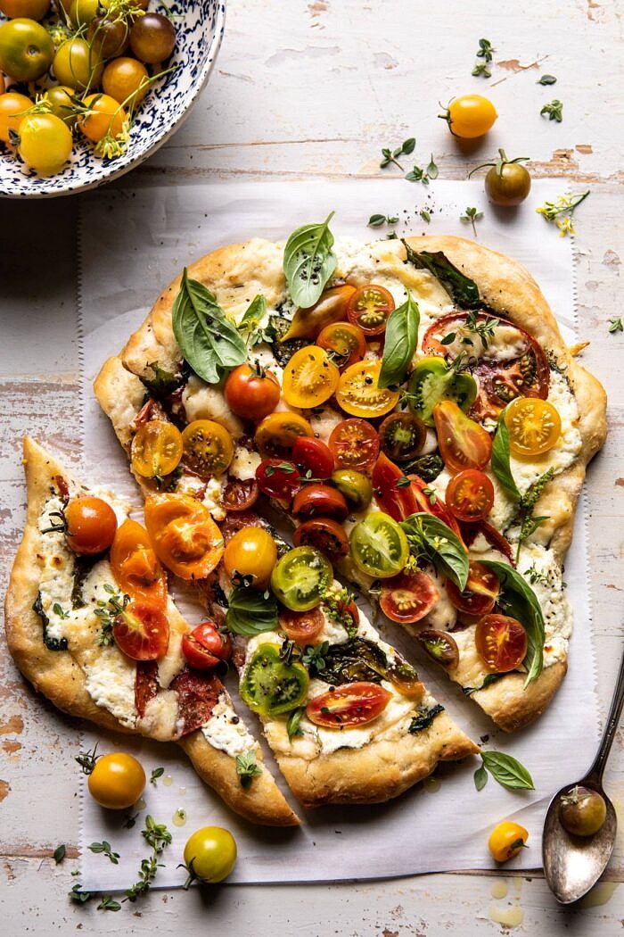 Herbed Butter Heirloom Tomato Pizza | halfbakedharvest.com #pizza #easyrecipe #tomatoes overhead photo of Herbed Butter Heirloom Tomato Pizza with 2 pieces of pizza cut