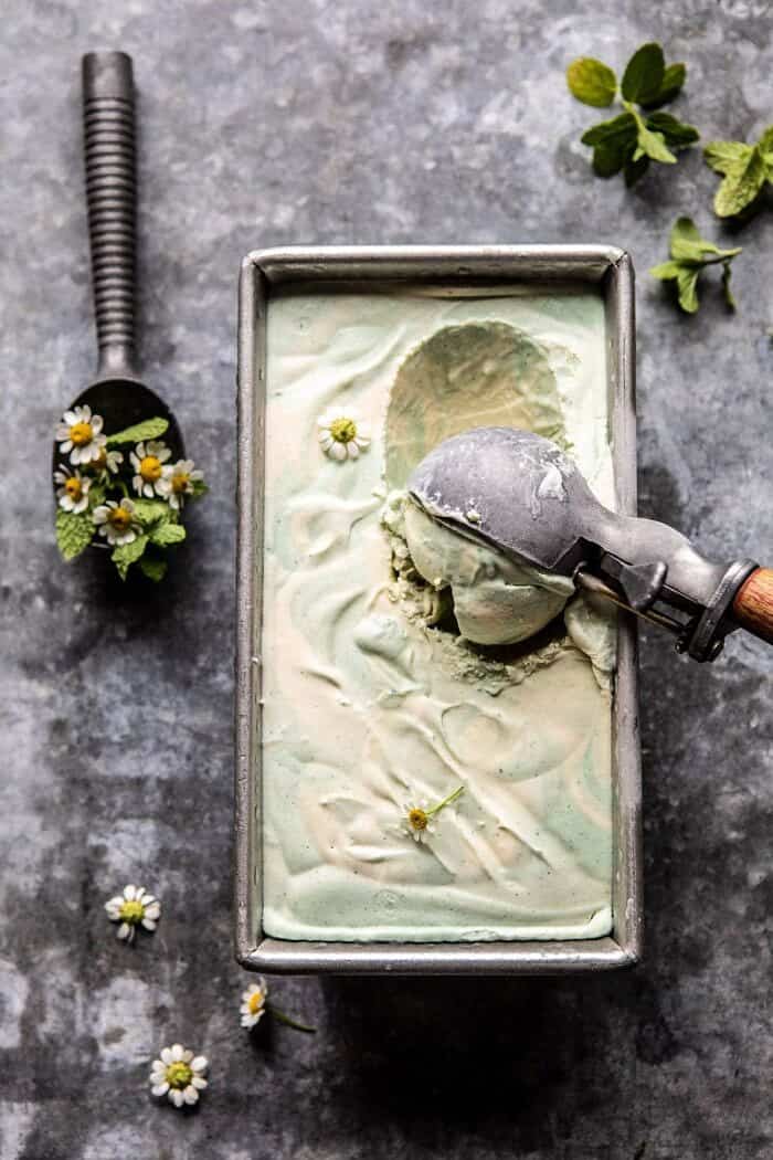 No Churn Minted White Chocolate Swirled Ice Cream | halfbakedharvest.com #icecream #easyrecipes #dessert #nochurnicecream overhead photo of No Churn Minted White Chocolate Swirled Ice Cream with ice cream scoop in ice cream scooping out first scoop of ice cream