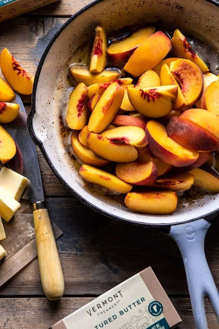 overhead photo of sliced peaches in skillet with browned butter before baking