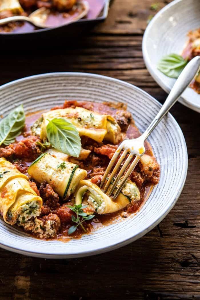 Spicy Pesto and Cheese Stuffed Zucchini Involtini | halfbakedharvest.com #zucchini #cheese #Italian #easyrecipes side angled photo of Spicy Pesto and Cheese Stuffed Zucchini Involtini on a plate with fork in a zucchini to reveal the cheese inside